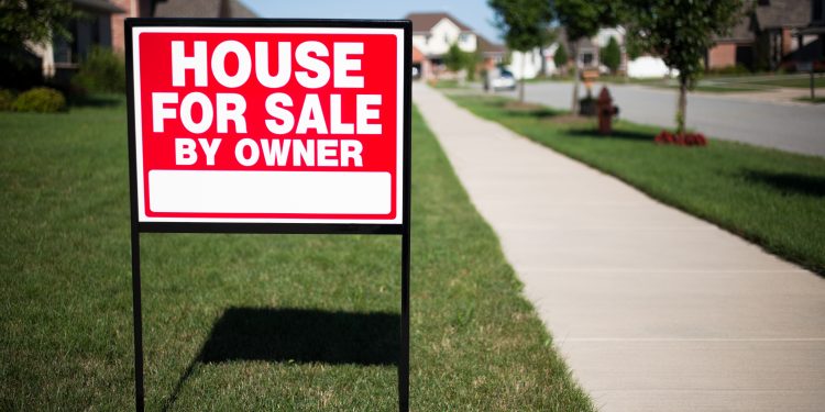 House For Sale By Owner Sign in a front yard of a home