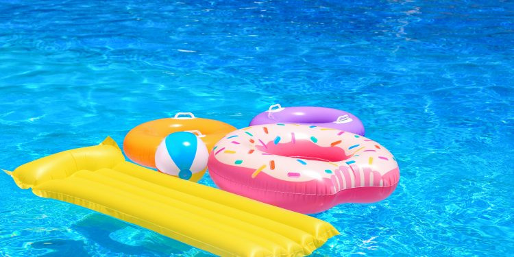 Inflatable rings, mattress and ball in blue swimming pool