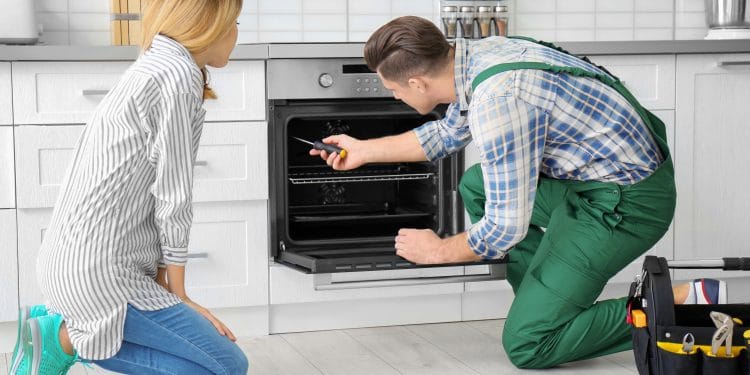 Housewife with worker near oven in kitchen
