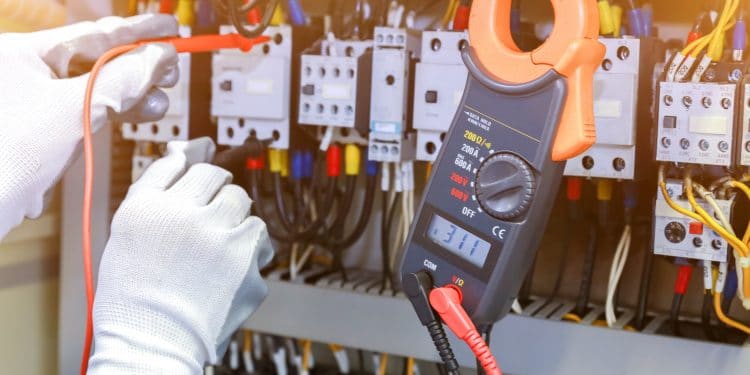 electrician measurements with multimeter tester in control panel.