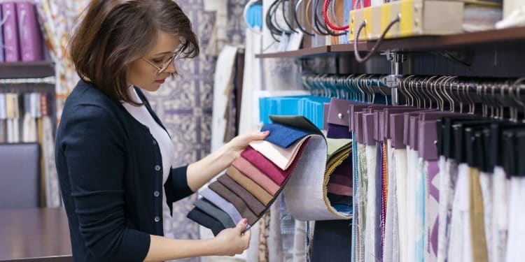 Woman designer, decorator chooses fabrics for curtains, pillows, embroidering fabrics, carpets in the textile show room