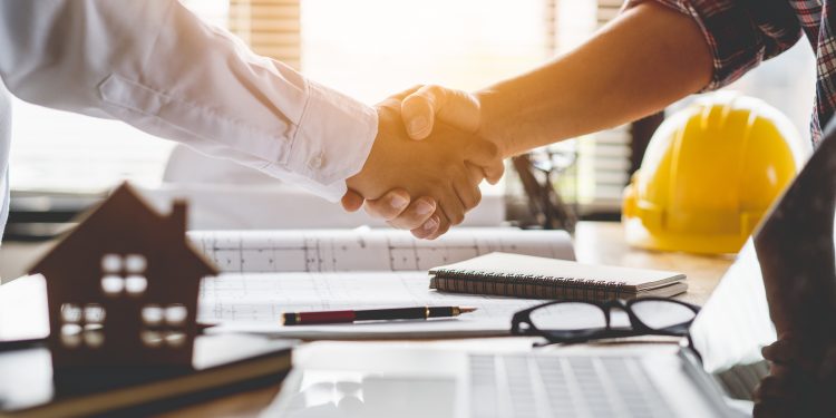 Client shaking hands with contractor after confirm blueprint to renovate house.