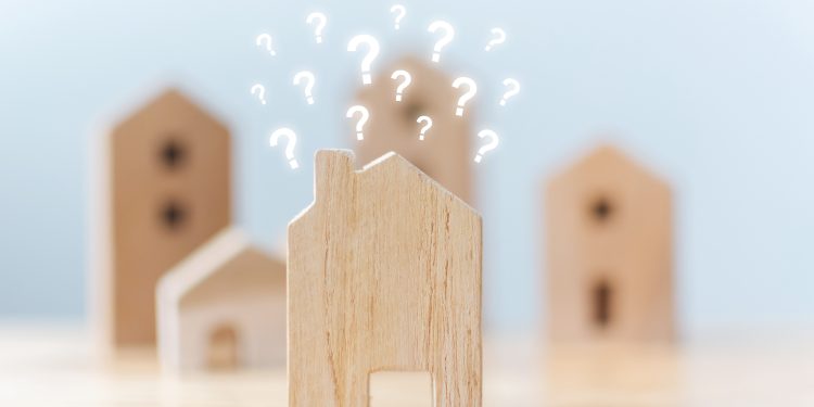 Real estate developer and managing property investment concept. Selective focus wooden houses with question mark on table
