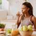 Water before breakfast. Slim and fit woman with many little braids drinking water before having breakfast