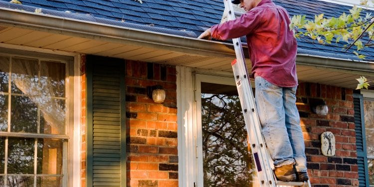 Man Cleaning Gutters on Ladder