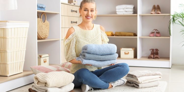 Woman with stacks of clean clothes at home