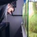 Young man pruning the plants in his aquarium. Concentration face.