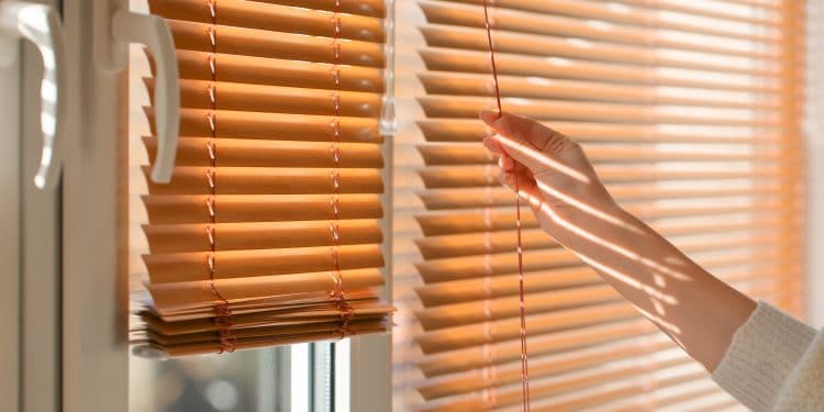 Woman opening blinds on window