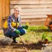 Attractive young blond woman sitting,working in her garden. Uniform, gloves, garden tools