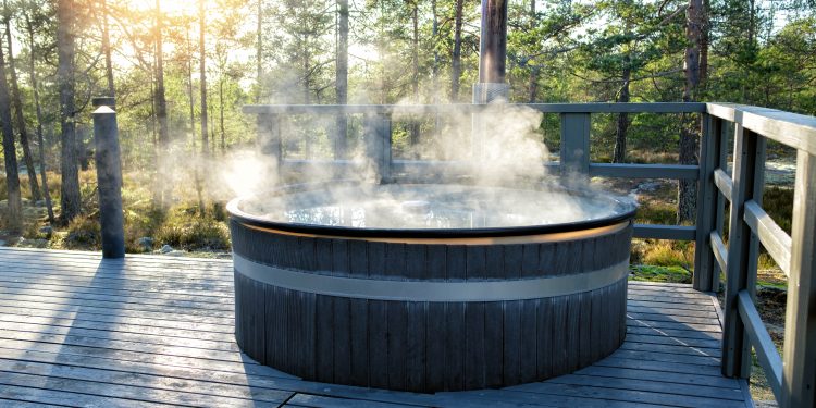 Modern big barrel outdoor hot tub in the middle of forest. The hot tub's soothing warm water relaxes muscles and eases tensions, so your worries can simply melt away.