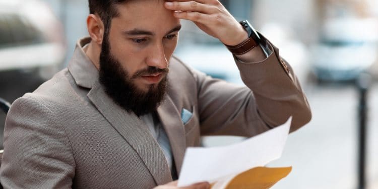 Big debt alert. A shocked man reads a court letter. Death of a loved one, increased mortgage payments.
