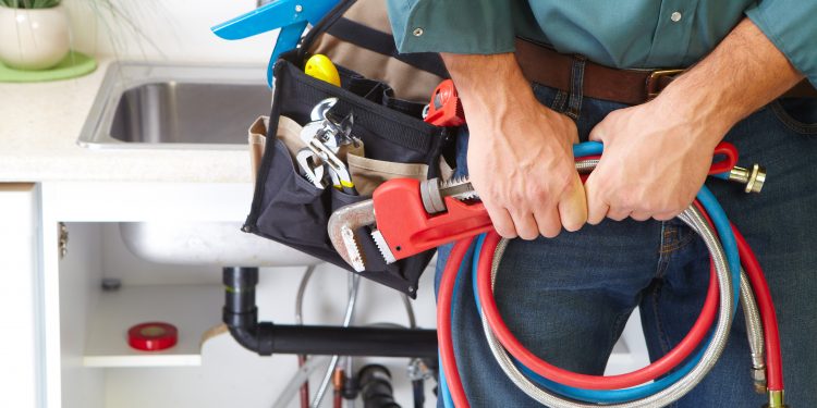 Plumber with Plumbing tools on the kitchen. Renovation.