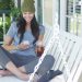 Young woman texting and sitting on porch