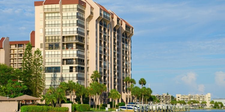 Beautiful waterside waterfront condominium luxury homes on a waterway with boats at the dock and green palm trees