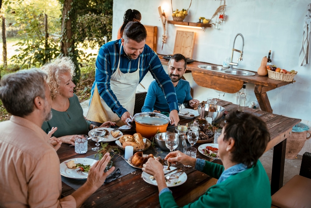 Man,Standing,Over,The,Dining,Table,With,Friends,And,Family,