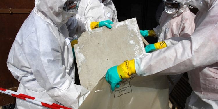 "Staff removing some asbestos in a post of transformer, Reflection of mask of man opposite was created for cannot be recognized"