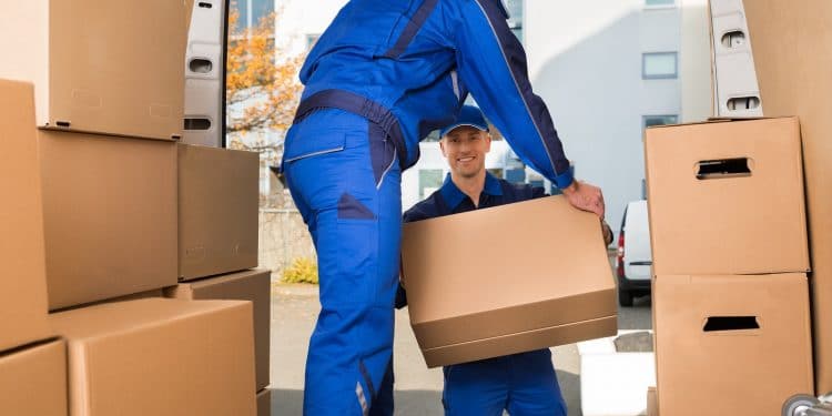 Full length of young male movers carrying sofa outside truck on street