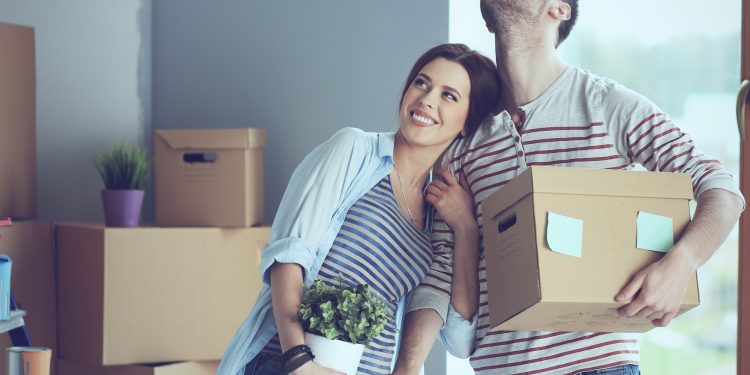 Happy young couple unpacking or packing boxes and moving into a new home.