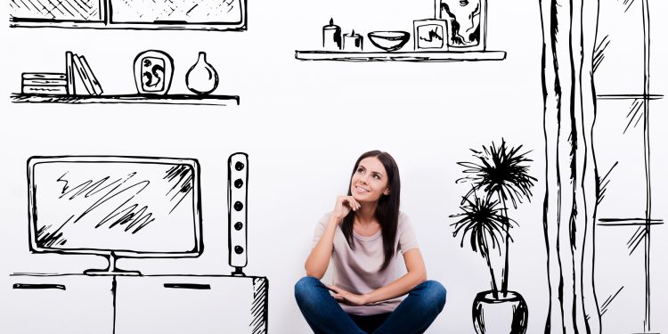 Dreaming about new apartment. Cheerful young woman smiling while sitting on the floor against white background with drawn home interior